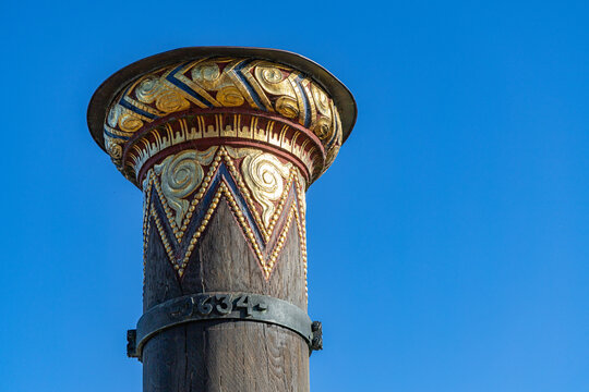 View of the ornate gold and red carvings on the Stormflodssojlen flood column against a clear blue sky in Ribe, Denmark.
