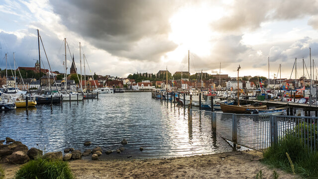 View of the historic harbor filled with sailboats and yachts under a dramatic cloudy sky in Flensburg, Schleswig-Holstein, Germany.