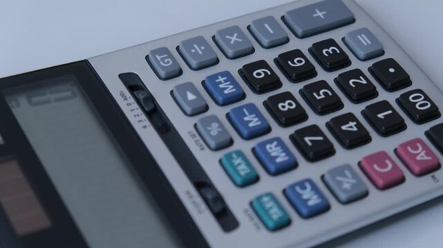 Close up angle of a silver and black electronic desktop calculator keyboard with colorful buttons