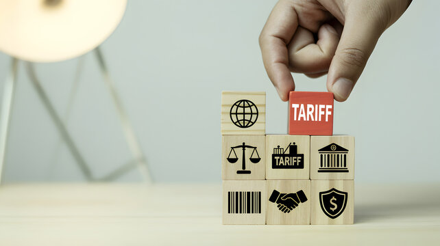 Hand stacking wooden blocks with tariff symbol and global trade icons representing economic policy