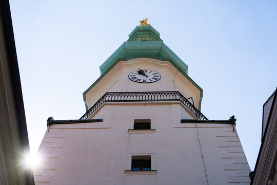 View of the historic Michael's Gate tower featuring its white facade, clock face, and green copper spire under a clear sky in Bratislava, Bratislava Region, Slovakia.