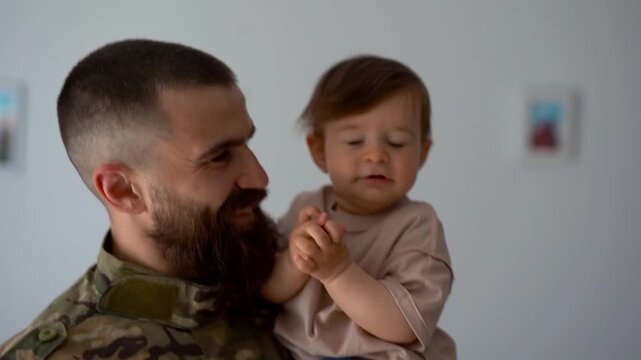Male soldier wearing military uniform while having tender moment with baby son at home - Homecoming, family and parenthood concept