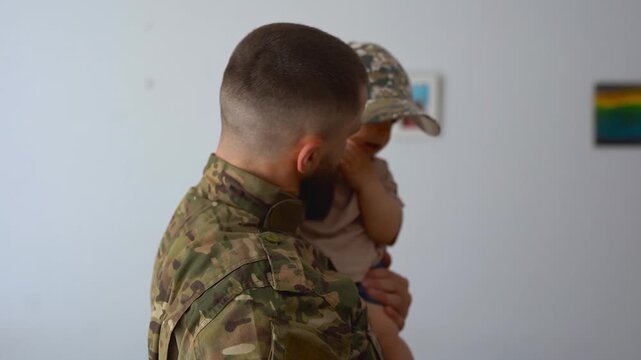 American male soldier in military uniform returning home to family - Father having playful time with baby son - Homecoming, happiness and lifestyle concept