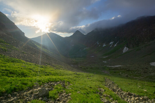 View of Smutne sedlo in Western Tatras with green grassy slopes and rocky terrain under a bright sun and cloudy sky Ziar, Zilina Region, Slovakia.
