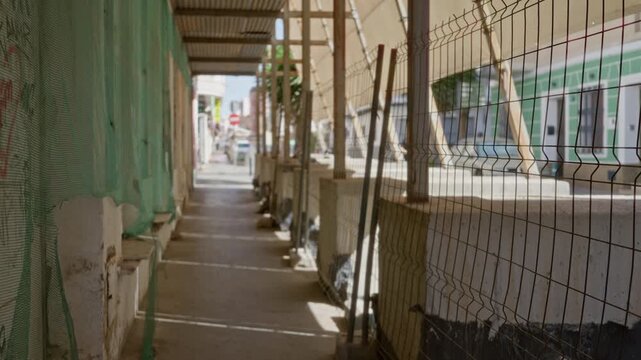 Defocused construction walkway framed by scaffolding and mesh fencing on a street background; background backplate copyspace.