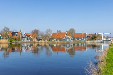 Obraz premium Zaandam, Netherlands. Scenic view of historic green wooden houses at Zaanse Schans with perfect water reflections on a calm sunny day.