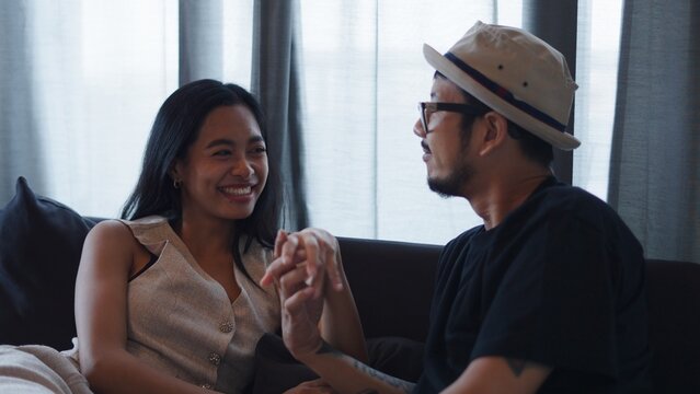 Young couple enjoying conversation, holding hands, and sharing happy moments indoors