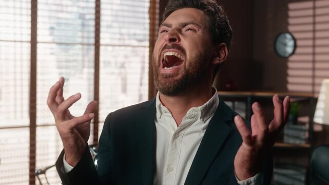 Funny emotional Caucasian middle-aged business man looking at camera laughing with evil raising hands happy adult businessman 40s male laugh maniacal laughter fun joy agent psycho emotion in office