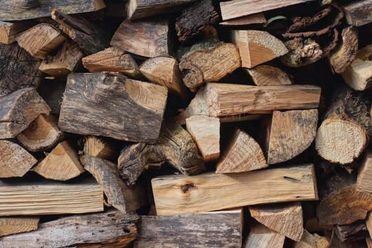 brown wood texture from heap of pine firewood against the wall in the street