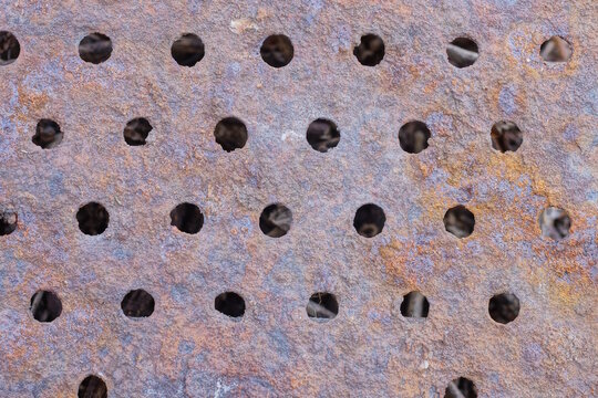 brown metal texture of rusty iron wall with a row of round holes