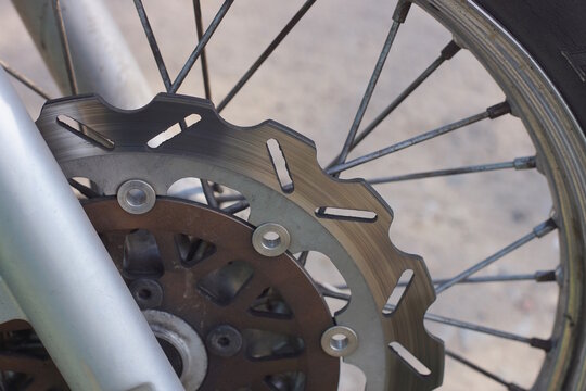 one gray black wheel on a motorcycle fork on a gray background on a summer city street