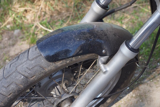 one gray black wheel on a motorcycle fork on a gray background on a summer city street