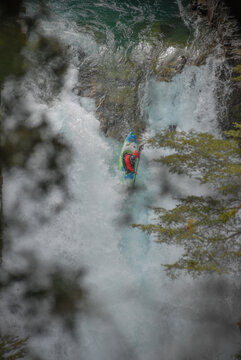 View of a kayaker navigating the white water rapids of the Rio Manso surrounded by lush green trees in San Carlos de Bariloche, Rio Negro, Argentina.