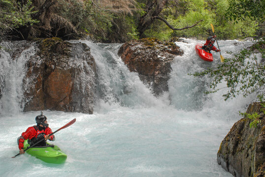 View of kayakers navigating the white water rapids of the Rio Manso waterfall surrounded by lush forest San Carlos de Bariloche, Rio Negro, Argentina.