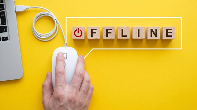 Offline text on wooden blocks with power icon, hand clicking computer mouse on yellow background, digital detox and internet connectivity concept