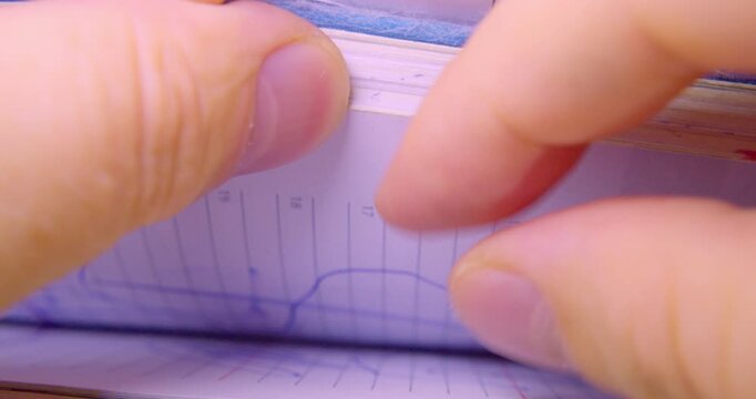 Paperwork in an office. Fingers flipping through a stack of documents. Searching for information. Macro photography.