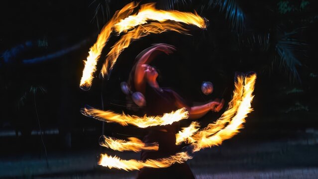 Dynamic fire dancer twirls flaming poi in a mesmerizing, motion-blurred nighttime performance