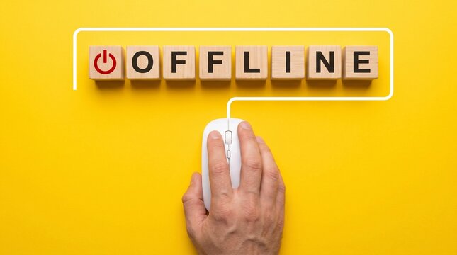 Offline text on wooden blocks with computer mouse, digital detox and internet disconnection concept, hand clicking mouse on yellow background