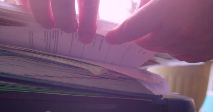The hands of a person searching for a document in a stack of papers. Information search. Close-up shot.