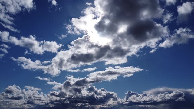 Cinematic 4k aerial drone footage of bright sun shining through dark and white clouds, dramatic blue sky cloudscape, sun flare and sunbeams, Backlit, Sunburst, and Dramatic view