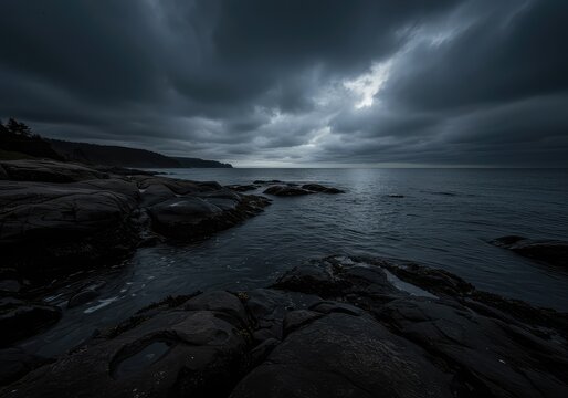 A moody, tranquil coastal landscape featuring dark water washing onto a rugged shore beneath an expansive, overcast sky ,stone ,atmospheric ,water