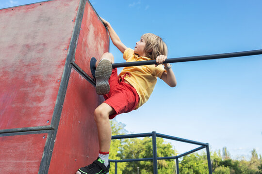 preteen boy maturely climbs sports structure at parkour playground. Active youth, healthy lifestyle, vitality, strength, joy, motivation to move. Sports activities for children, physical development