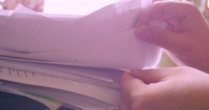 Hands of a businessman searching for a needed document in a stack of papers. Paperwork. Information search. Close-up shot.