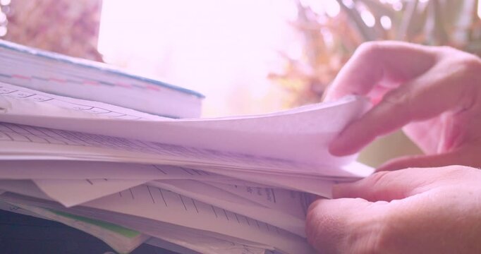 Hands of a businessman searching for a needed document in a stack of papers. Paperwork. Information search. Close-up shot.