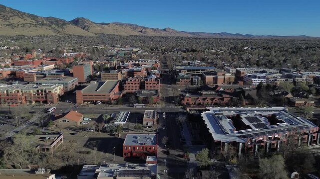 Central Boulder urban grid shows dense blocks north of Canyon Blvd, midrise brick buildings, structured downtown streets. Mixed roofing, scattered foliage, crisp daylight layered texture, CO