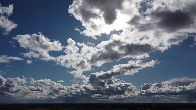Cinematic 4k aerial view of sunbeams breaking through white fluffy clouds, deep blue sky with moving cloudscape, bright sun star flare, high altitude drone footage, nature background