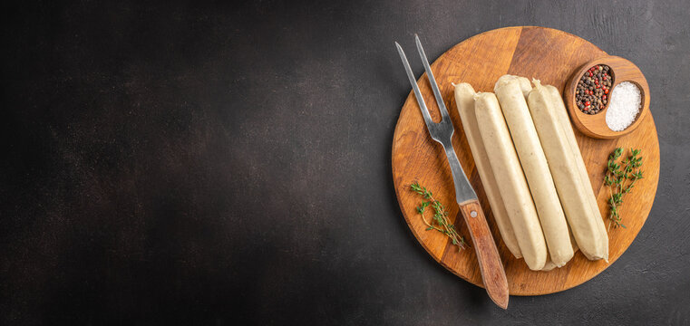 White sausages on wooden board with spices