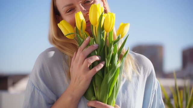 Happy young woman standing outdoors holding bouquet of fresh tulips, enjoying sunny spring weather. Floral lifestyle, natural beauty, and joyful seasonal celebration concept.