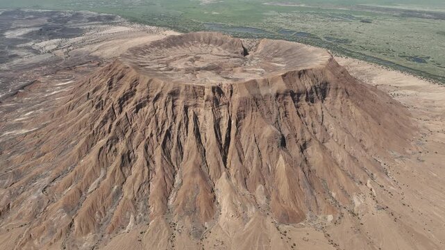 Aerial view of a massive volcanic crater with eroded slopes and arid plains in the Danakil Desert Dalol, Afar, Ethiopia.