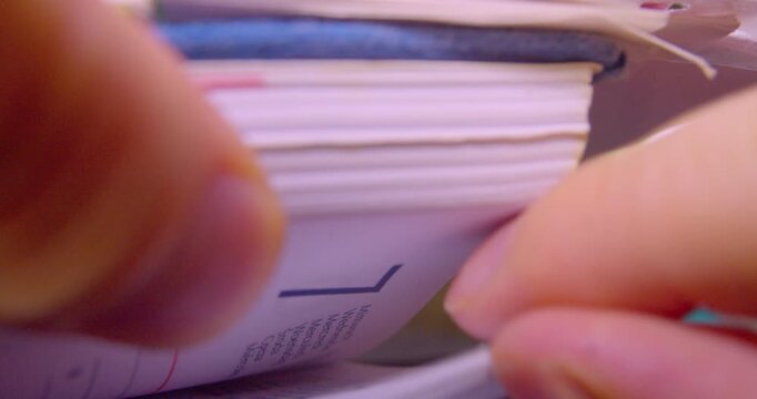 Paperwork in an office. Fingers flipping through a stack of documents. Searching for information. Macro photography.