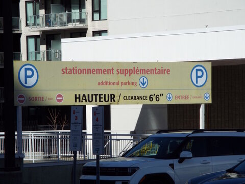 Gatineau, Quebec, Canada &ndash; April 19, 2026: A yellow bilingual parking sign indicates additional parking and a "height clearance" of 6'6" for an underground garage on Boulevard Saint-Joseph.