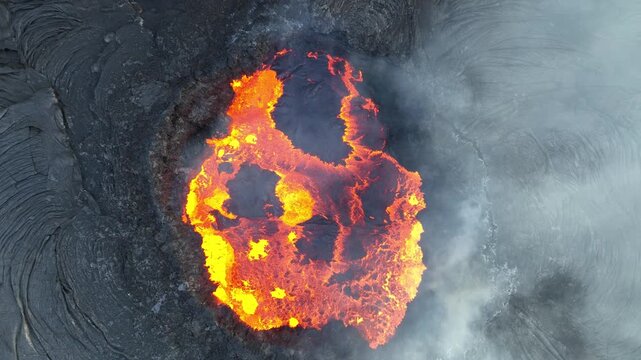 Aerial view of glowing molten lava inside a volcanic crater with smoke and dark basaltic rock in the Danakil Desert Dalol, Afar, Ethiopia.