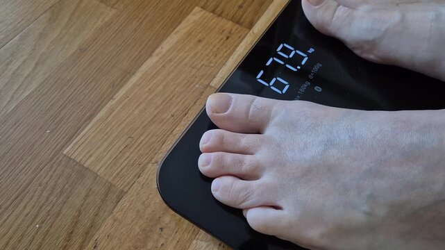 Person stepping on digital bathroom scale showing body weight close up healthy lifestyle concept