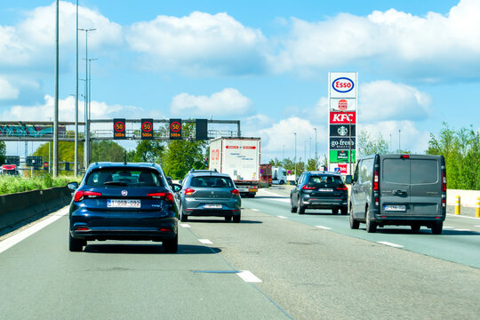 Ghent, Belgium - April 20, 2026: Dense traffic on the E17 highway near Drongen, featuring overhead digital displays with a 50 km h speed warning and a service station pylon with Esso, Burger King