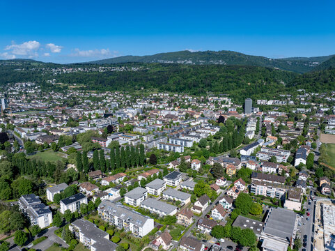 Aerial view of the residential district of Boezingenfeld Champ with modern apartment buildings and lush green trees against forested hills in Biel Bienne, Canton of Bern, Switzerland.
