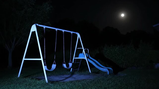 Nighttime Playground with Illuminated Swing Set and Slide Under Moonlight.
