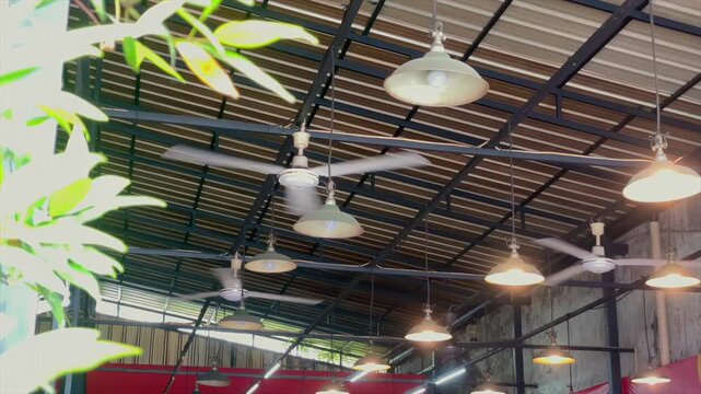 Low angle view of hanging lamps and spinning ceiling fans under the roof