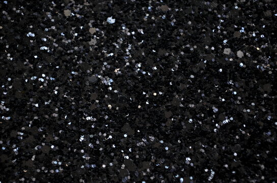 Black background with a lot of black glitter. The glitter is scattered all over the background