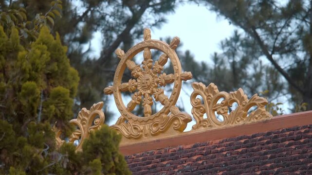 A golden Dharmachakra, also known as the Wheel of Dharma or Wheel of Law is placed on a traditional Asian tiled roof of the Truc Lam Zen Monastery in Da Lat, Vietnam