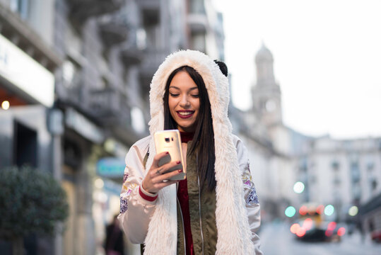 woman looking smartphone with panda clothing in city