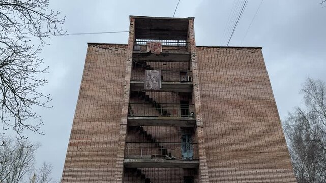Brick building exterior hanging carpets balconies, weathered hostel end with open staircases and concrete landings, patterned rugs