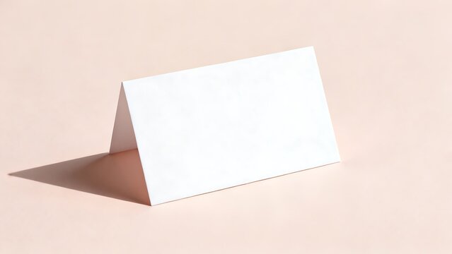 Blank white tent card stands upright on a pink background with soft shadow.