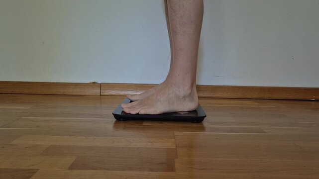 Man stepping on digital bathroom scale at home checking body weight healthy lifestyle concept