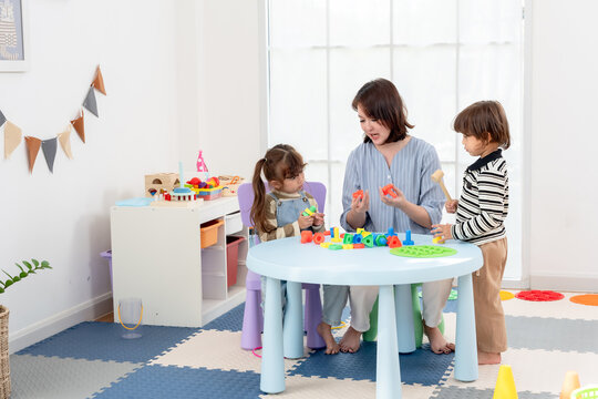 Single mother guiding children gentle care, explaining educational bolt toy, toddler son listens, preschool daughter assembles pieces, creative play activities, family bonding without screen indoors