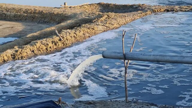 Irrigation Water Flow from PVC Pipe to Salt Pond Pond in the Afternoon at Pamekasan, Indonesia.