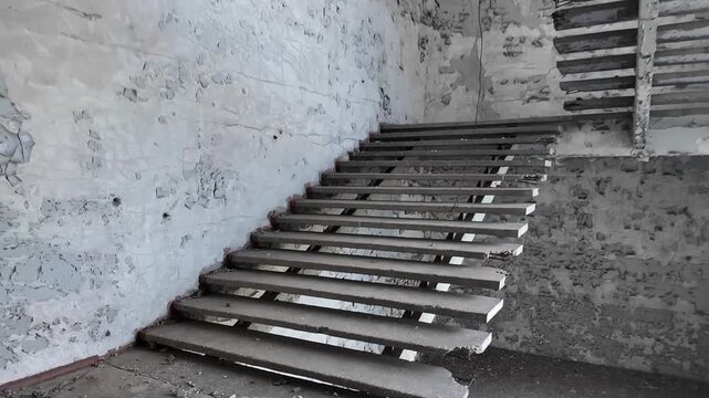 Camera approaching a ruined concrete staircase in an abandoned building
